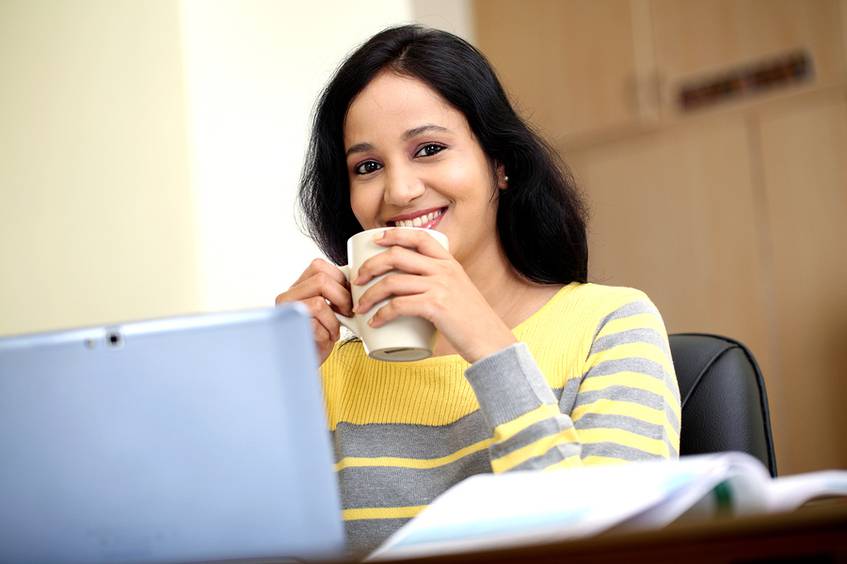 Woman sitting in front of her laptop drinking coffee.